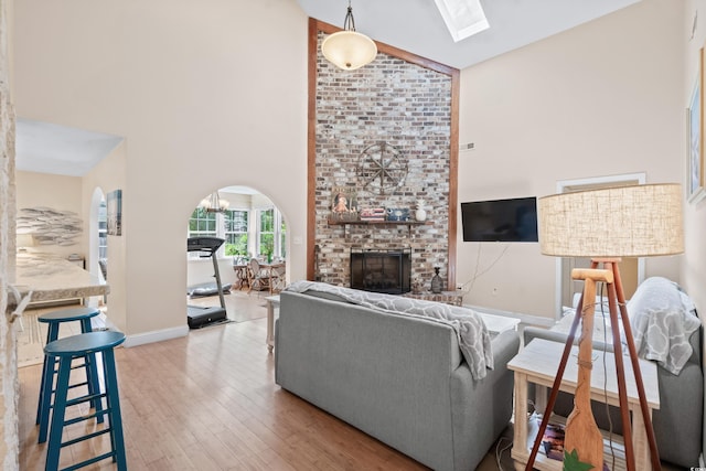 living room featuring light hardwood / wood-style flooring, high vaulted ceiling, and a brick fireplace