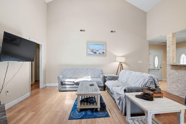 living room with light hardwood / wood-style flooring, high vaulted ceiling, and decorative columns