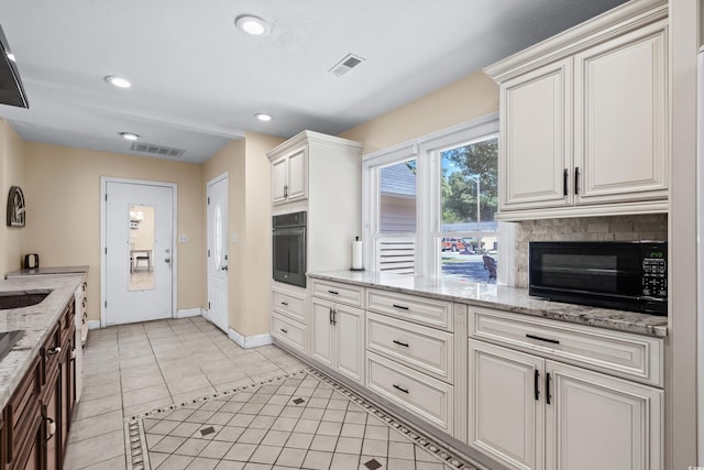 kitchen featuring black appliances, light stone counters, light tile patterned floors, and a fireplace