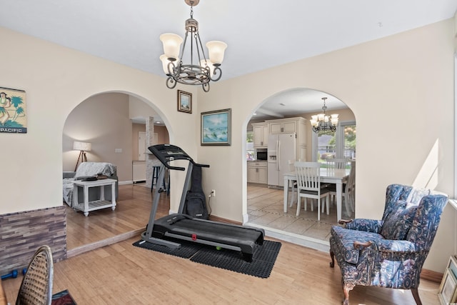 workout room featuring light wood-type flooring and a notable chandelier