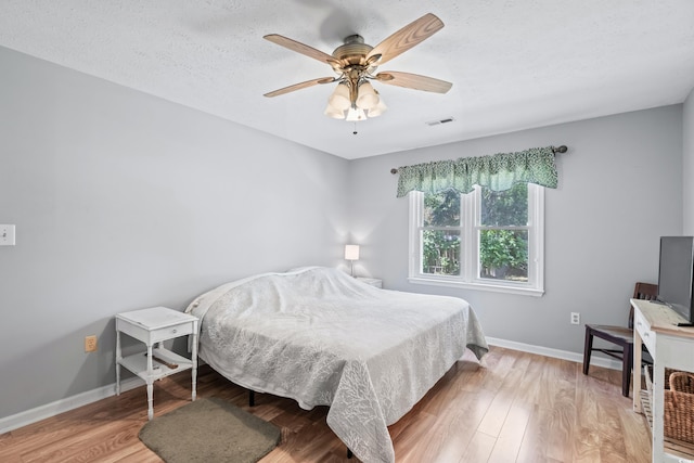 bedroom with hardwood / wood-style flooring, ceiling fan, and a textured ceiling