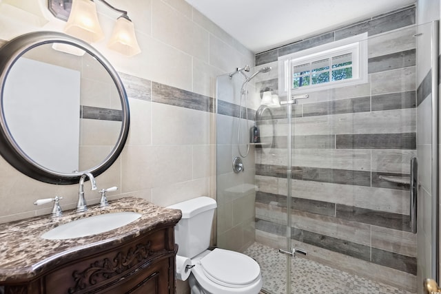 bathroom featuring tile walls, vanity, an enclosed shower, and toilet