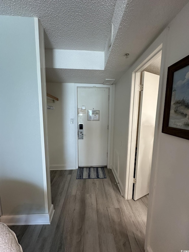 hallway featuring wood-type flooring and a textured ceiling