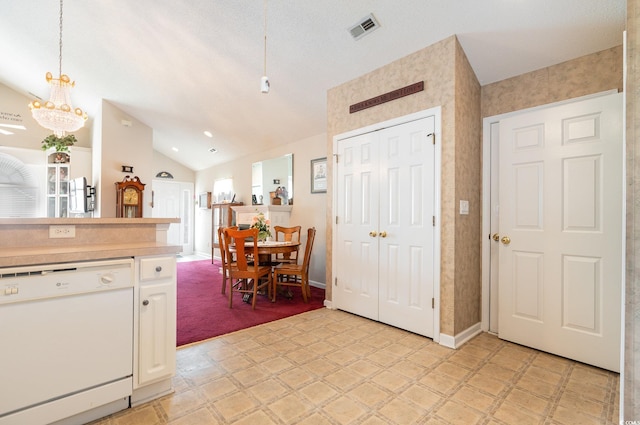 kitchen featuring decorative light fixtures, light tile flooring, dishwasher, and vaulted ceiling