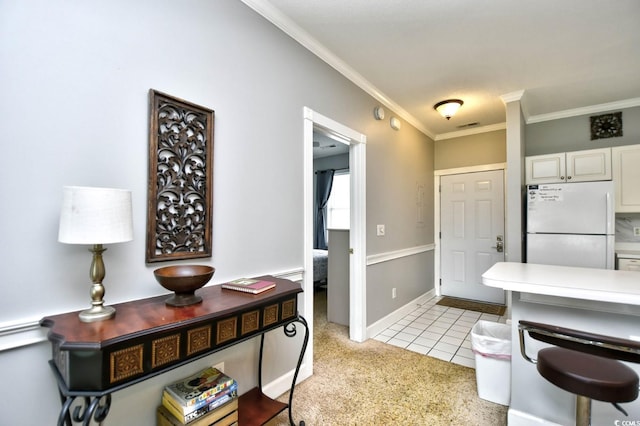 kitchen featuring white cabinets, ornamental molding, white fridge, and light tile flooring