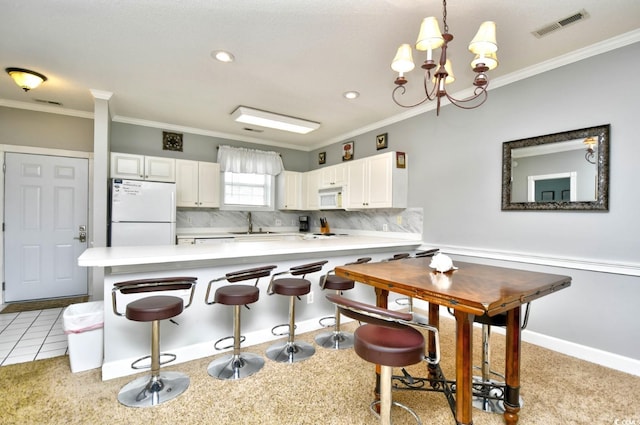 kitchen featuring white appliances, pendant lighting, a notable chandelier, tasteful backsplash, and light tile floors