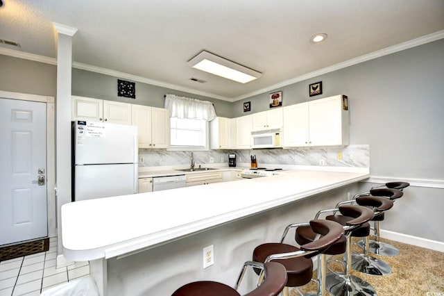 kitchen featuring a breakfast bar, white appliances, backsplash, and kitchen peninsula