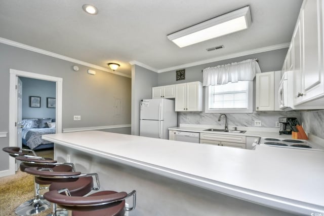 kitchen featuring white appliances, kitchen peninsula, sink, tasteful backsplash, and a kitchen bar