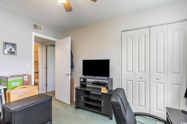 carpeted office space with ceiling fan and a textured ceiling