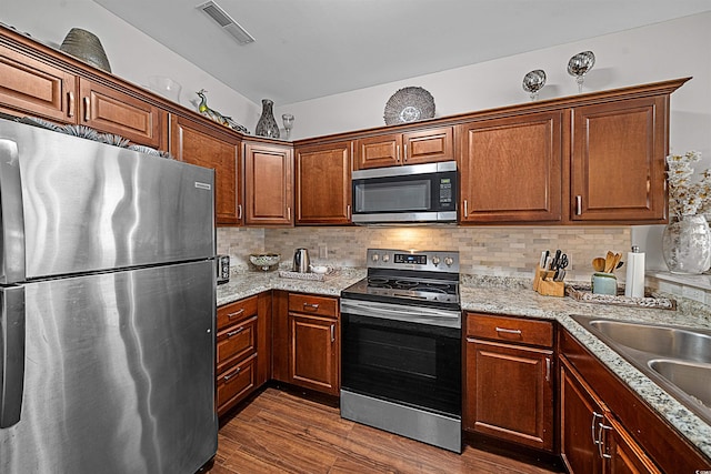 kitchen with light stone counters, stainless steel appliances, tasteful backsplash, dark wood-type flooring, and sink