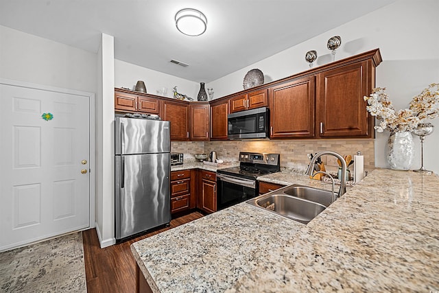 kitchen featuring light stone countertops, stainless steel appliances, dark hardwood / wood-style flooring, backsplash, and sink