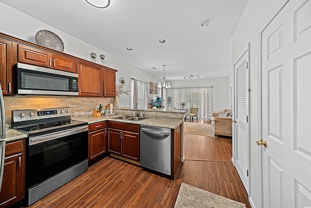 kitchen featuring stainless steel appliances, kitchen peninsula, sink, and dark wood-type flooring