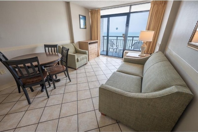 living room featuring light tile patterned floors, a water view, and floor to ceiling windows