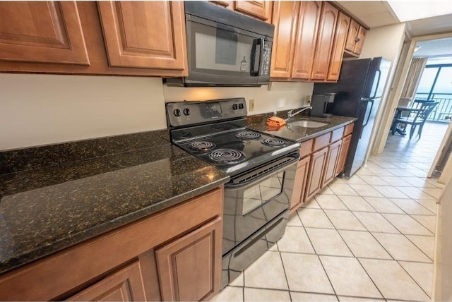 kitchen with light tile patterned floors, sink, dark stone counters, and black appliances