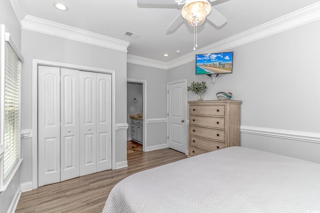 bedroom with crown molding, ceiling fan, a closet, and hardwood / wood-style floors