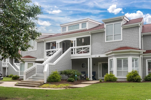 view of front facade with stairs, a shingled roof, and a front lawn