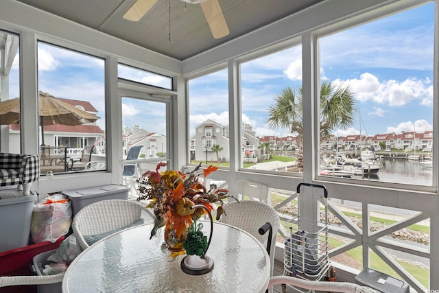 sunroom / solarium featuring a water view and ceiling fan