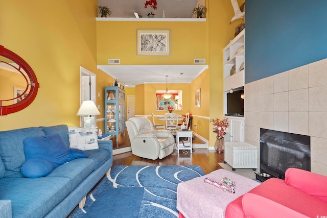 living room featuring a towering ceiling, a tile fireplace, and hardwood / wood-style floors