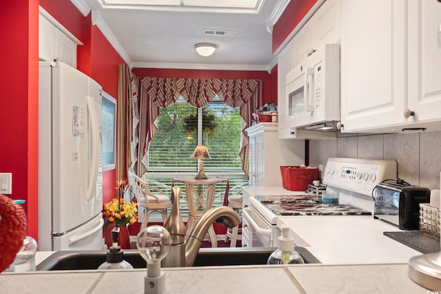 kitchen featuring decorative backsplash, white cabinets, a textured ceiling, crown molding, and white appliances