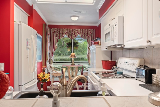 kitchen with white appliances, white cabinetry, crown molding, and visible vents