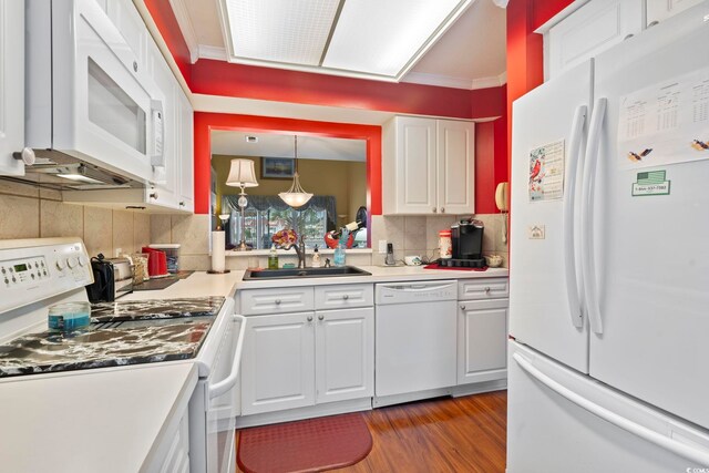 kitchen with wood finished floors, white appliances, white cabinets, a sink, and backsplash