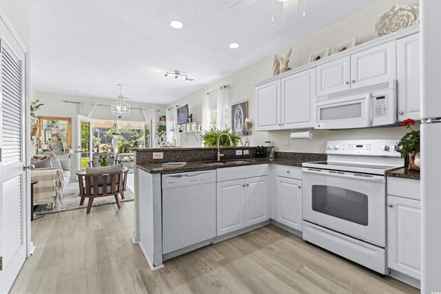 242 Sun Colony Blvd Unit 101, Longs, SC 29568 - kitchen with white appliances, light wood-style floors, a textured ceiling, white cabinets, and a peninsula