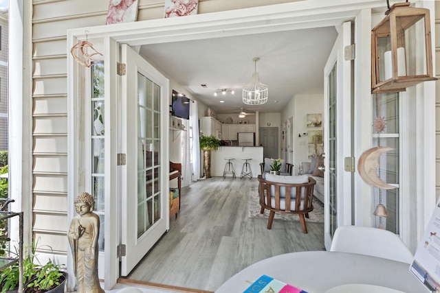 interior space with an inviting chandelier, french doors, and light hardwood / wood-style flooring