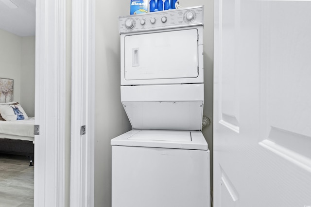 laundry area with light hardwood / wood-style flooring and stacked washer / dryer