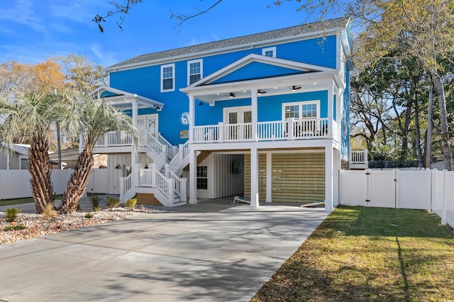 back of house featuring driveway, a gate, stairway, a carport, and a porch