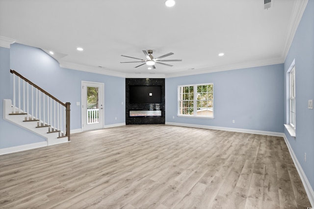 unfurnished living room with light wood-type flooring, a wealth of natural light, ornamental molding, and ceiling fan