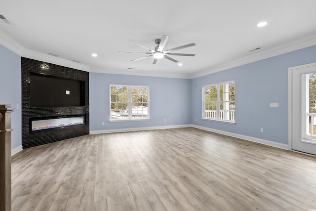 unfurnished living room with light wood-type flooring, a large fireplace, a wealth of natural light, and crown molding