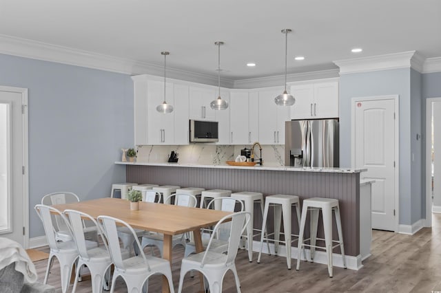 dining room featuring light wood finished floors, baseboards, recessed lighting, and ornamental molding