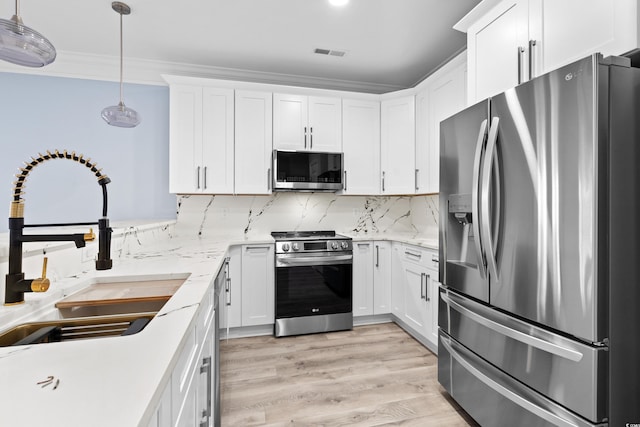 kitchen with pendant lighting, white cabinets, sink, decorative backsplash, and stainless steel appliances