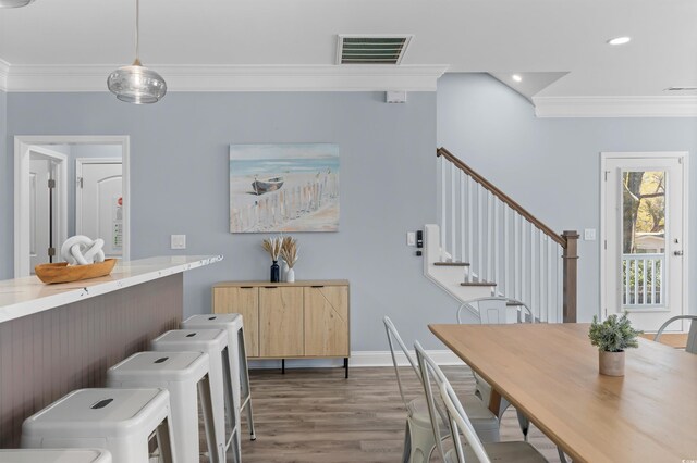 dining area featuring visible vents, wood finished floors, crown molding, and washing machine and clothes dryer