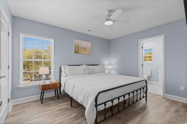bedroom with baseboards, connected bathroom, visible vents, and light wood finished floors