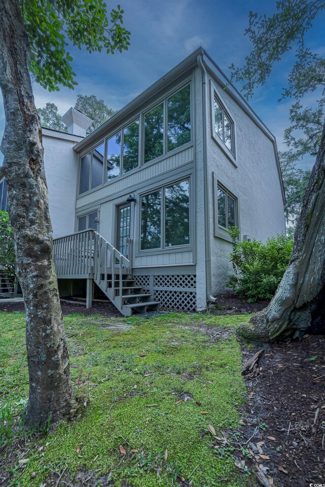 rear view of house featuring a wooden deck and a yard