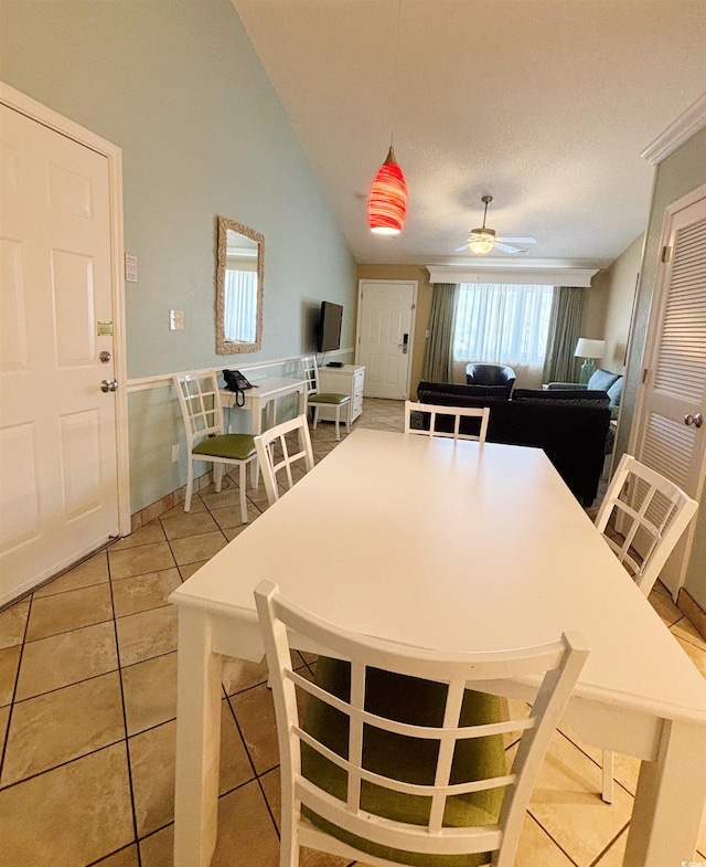 dining area with ceiling fan, vaulted ceiling, light tile flooring, and a wealth of natural light