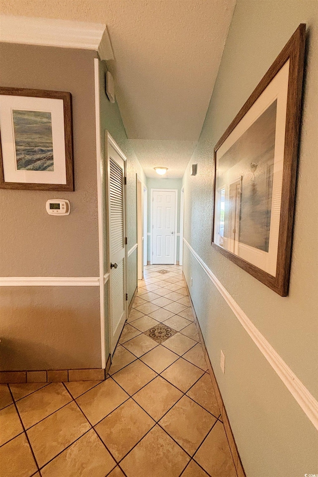 hall featuring a textured ceiling and light tile floors