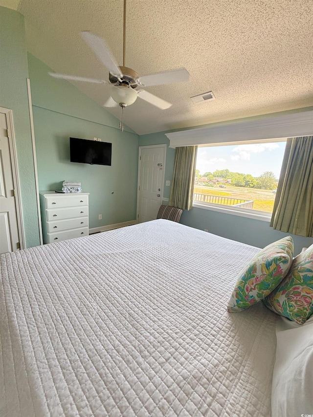 bedroom with ceiling fan, a textured ceiling, and lofted ceiling