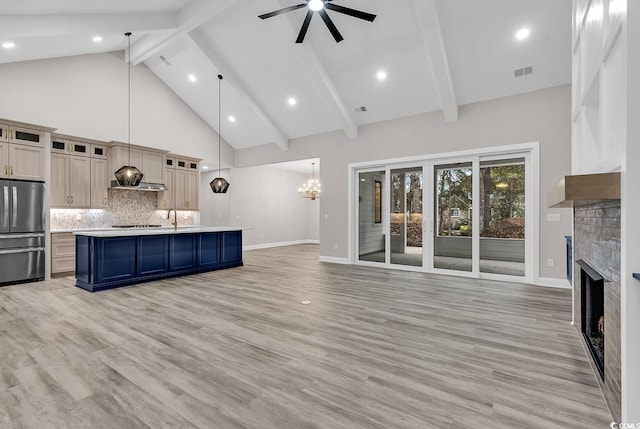 unfurnished living room with a fireplace, ceiling fan with notable chandelier, high vaulted ceiling, and light hardwood / wood-style flooring