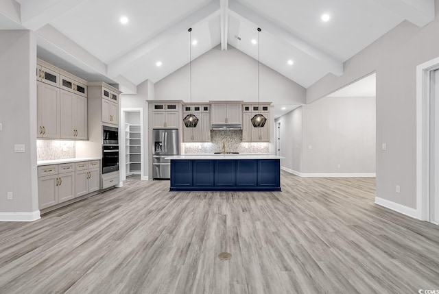 kitchen with pendant lighting, a kitchen island with sink, appliances with stainless steel finishes, and light hardwood / wood-style flooring