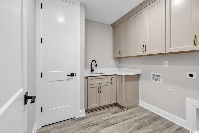 laundry area featuring electric dryer hookup, cabinets, sink, hookup for a washing machine, and light wood-type flooring