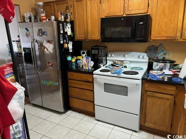 kitchen with white electric range oven, brown cabinets, black microwave, stainless steel refrigerator with ice dispenser, and light tile patterned flooring