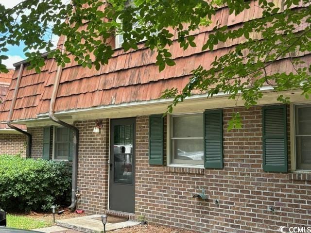 exterior space with brick siding and mansard roof