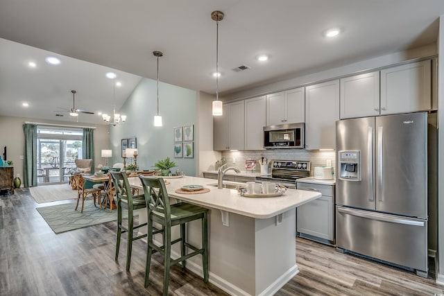 kitchen with light hardwood / wood-style flooring, stainless steel appliances, gray cabinets, backsplash, and lofted ceiling