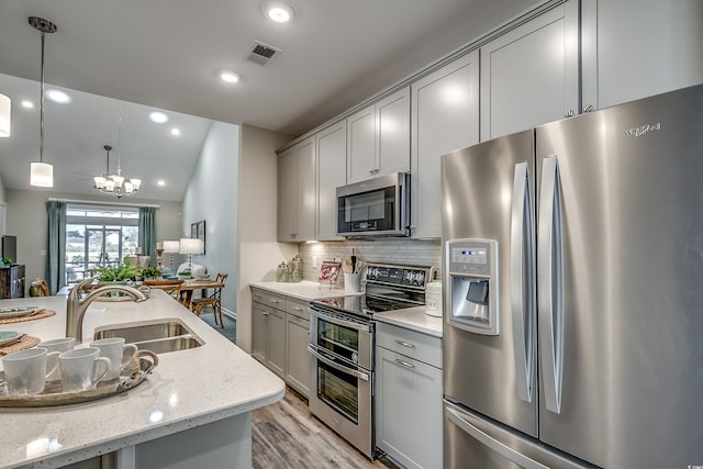 kitchen featuring light hardwood / wood-style flooring, stainless steel appliances, gray cabinets, backsplash, and sink