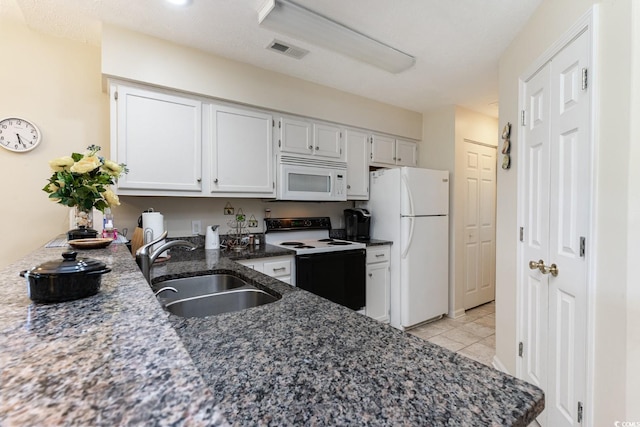 kitchen featuring white cabinetry, white appliances, dark stone counters, sink, and light tile flooring