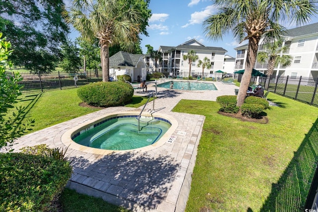 view of swimming pool with a community hot tub, a lawn, and a patio area