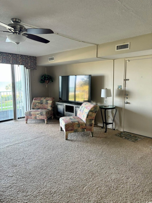 living room with a textured ceiling, carpet, and ceiling fan