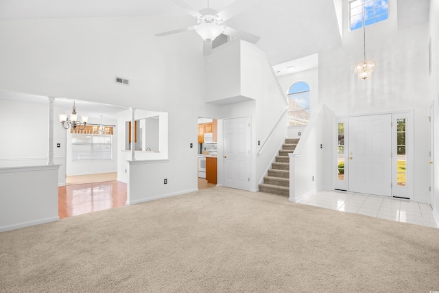 unfurnished living room featuring a chandelier, a towering ceiling, light colored carpet, baseboards, and stairs